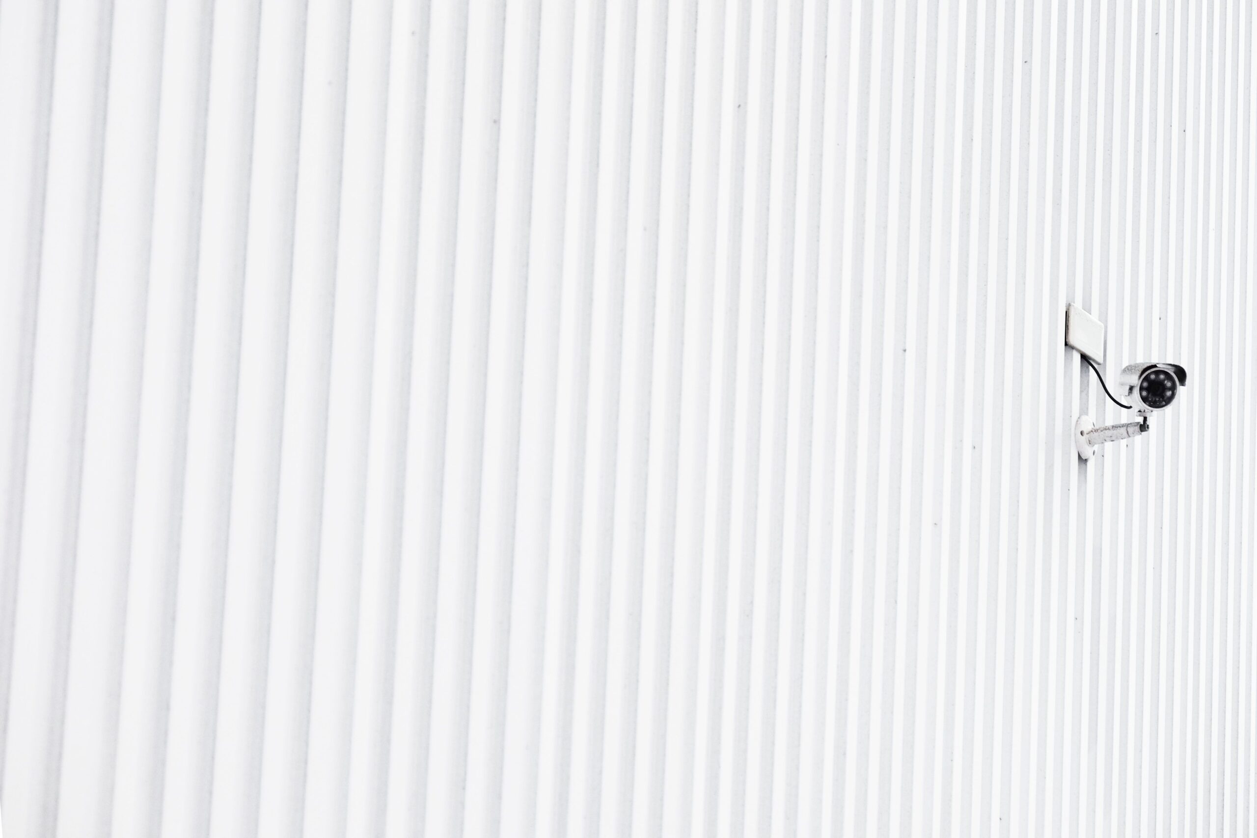 Instalación minimalista de una cámara de seguridad en una pared blanca, representando la ubicación estratégica.