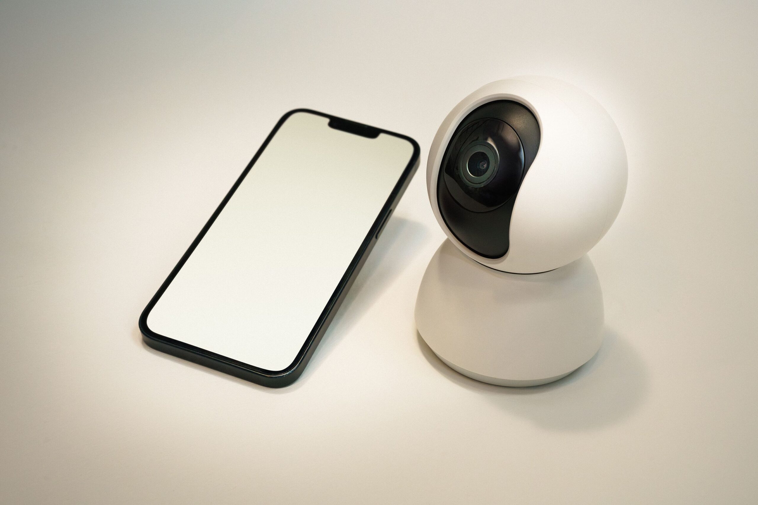 Cámara de seguridad inteligente junto a un smartphone, representando la configuración y gestión remota de dispositivos IP.