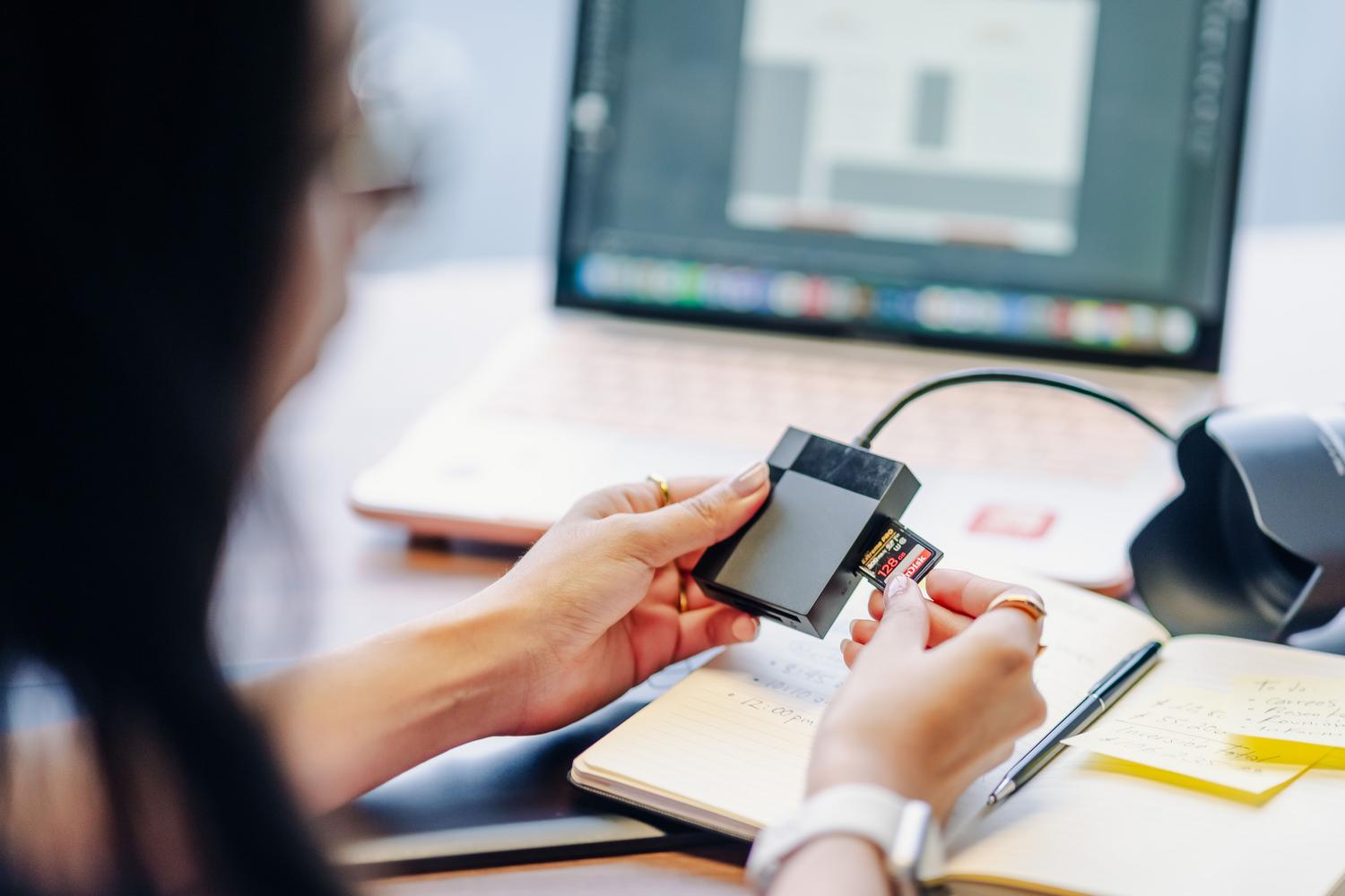Person inserting an SD card into a reader connected to a laptop to update the firmware