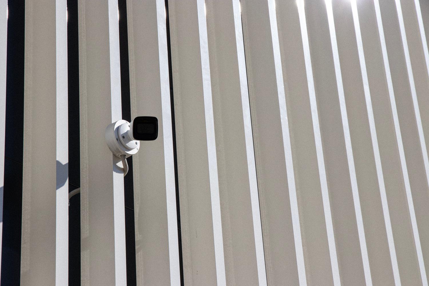 Cámara de seguridad profesional instalada en la fachada de un edificio moderno con líneas arquitectónicas limpias.