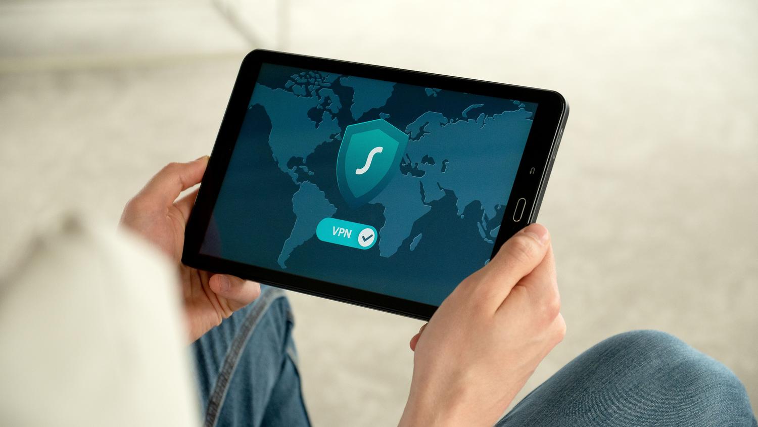 Persona utilizando una tablet con una aplicación de VPN activa, representando el acceso remoto seguro a los sistemas de vigilancia.
