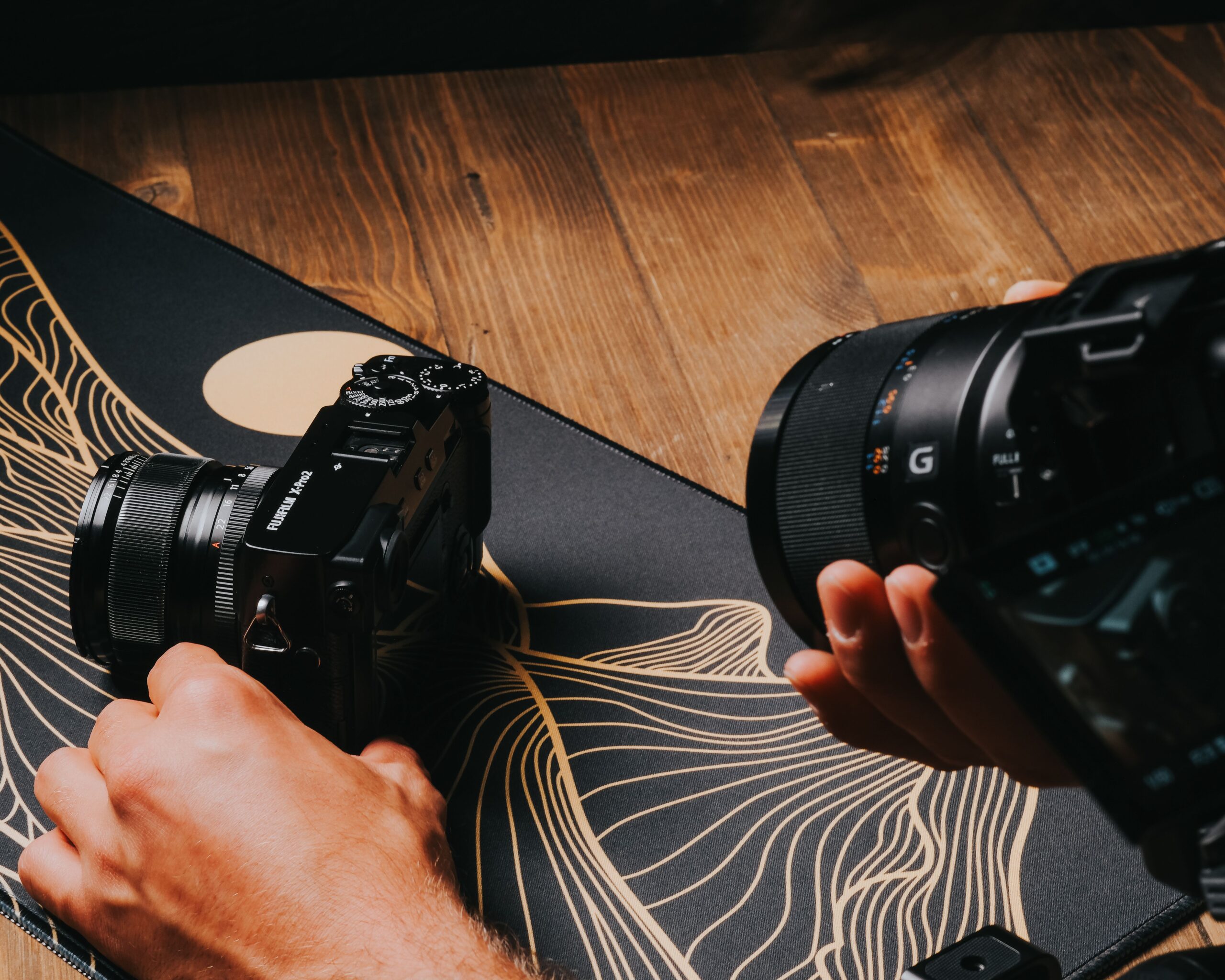 Manos de un fotógrafo manipulando cámaras mirrorless sobre un escritorio, representando el proceso de mantenimiento y actualización de equipo.