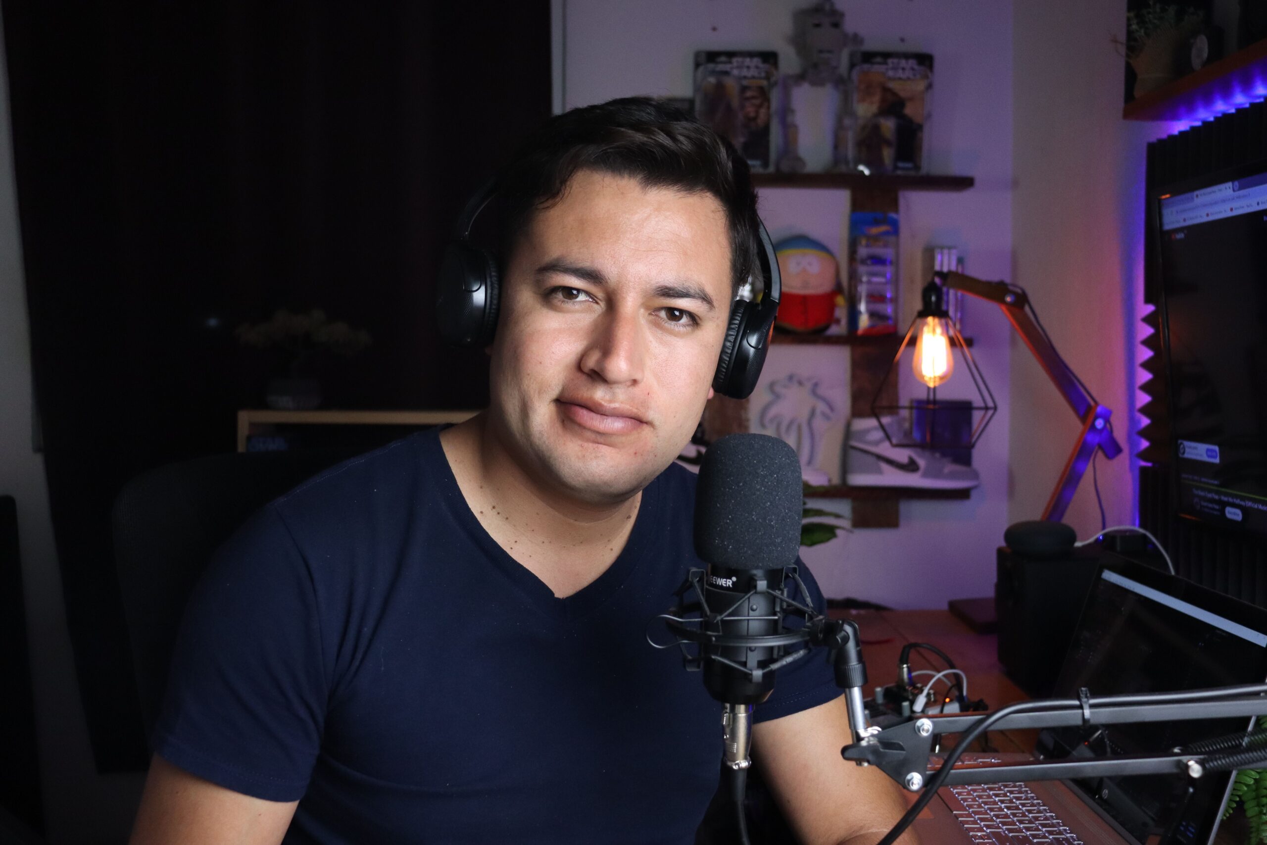 Hombre en un estudio casero con auriculares y micrófono profesional, representando la experiencia del usuario al configurar dispositivos de audio.