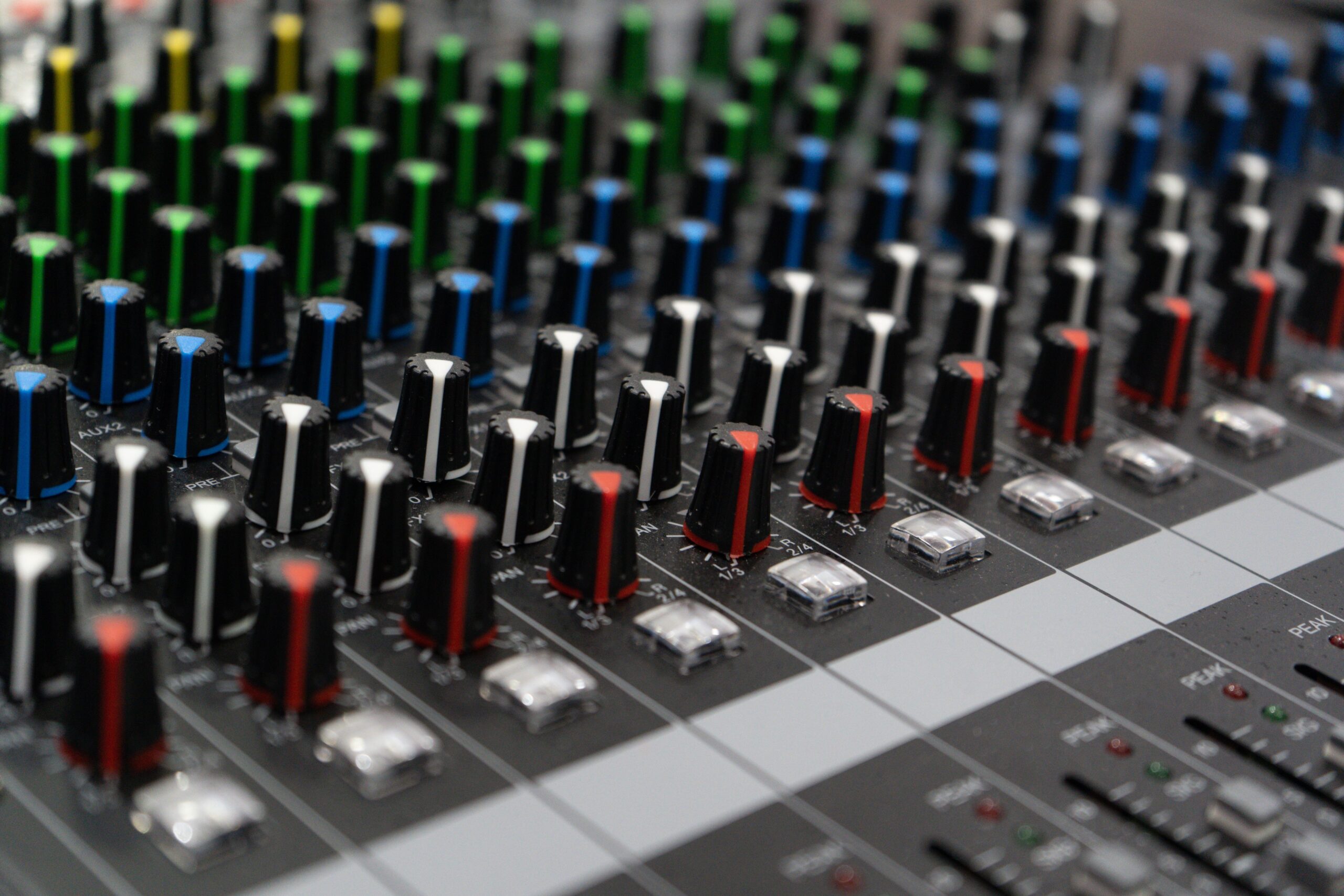 Vista artística de diales coloridos en una consola de sonido, enfatizando la complejidad técnica del equipo de audio.