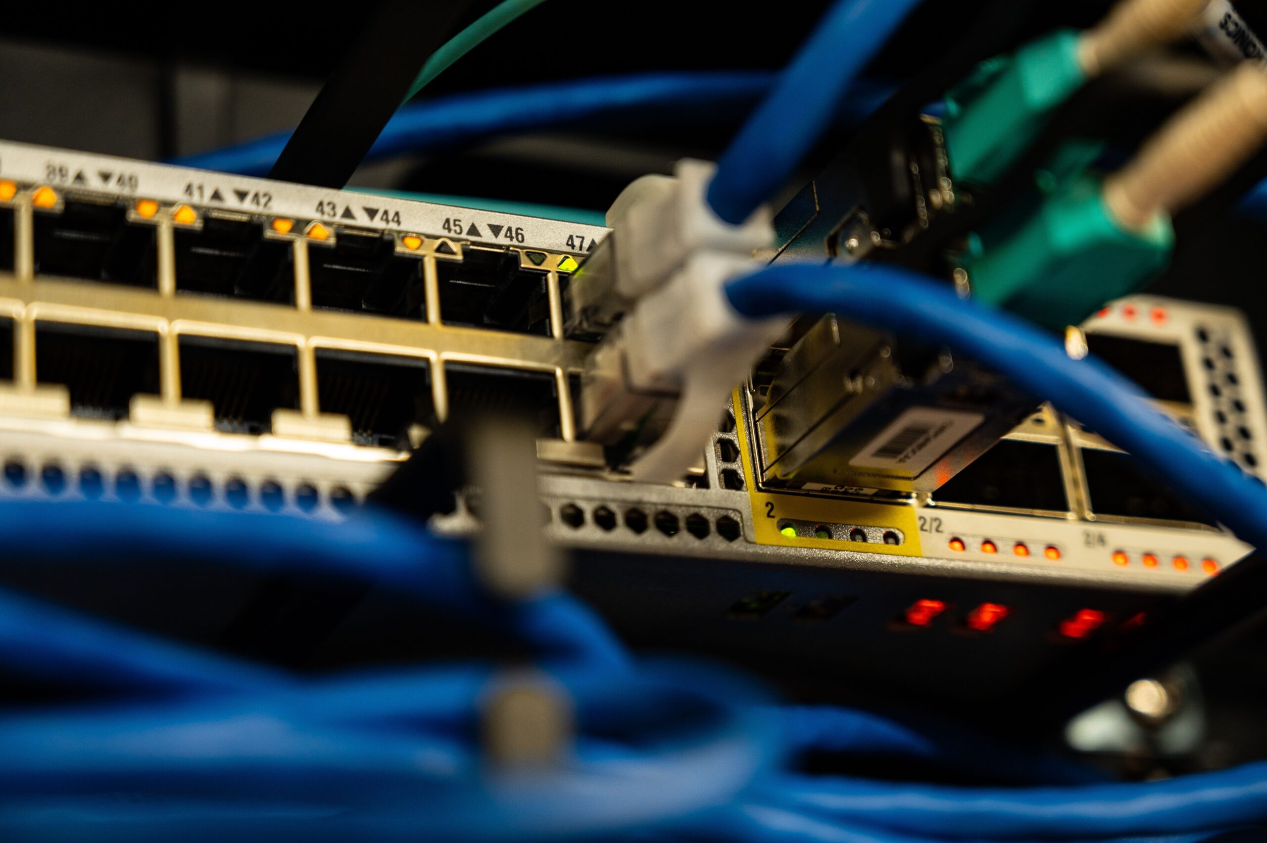 Close-up of blue Ethernet cables connected to a network switch with status LEDs.