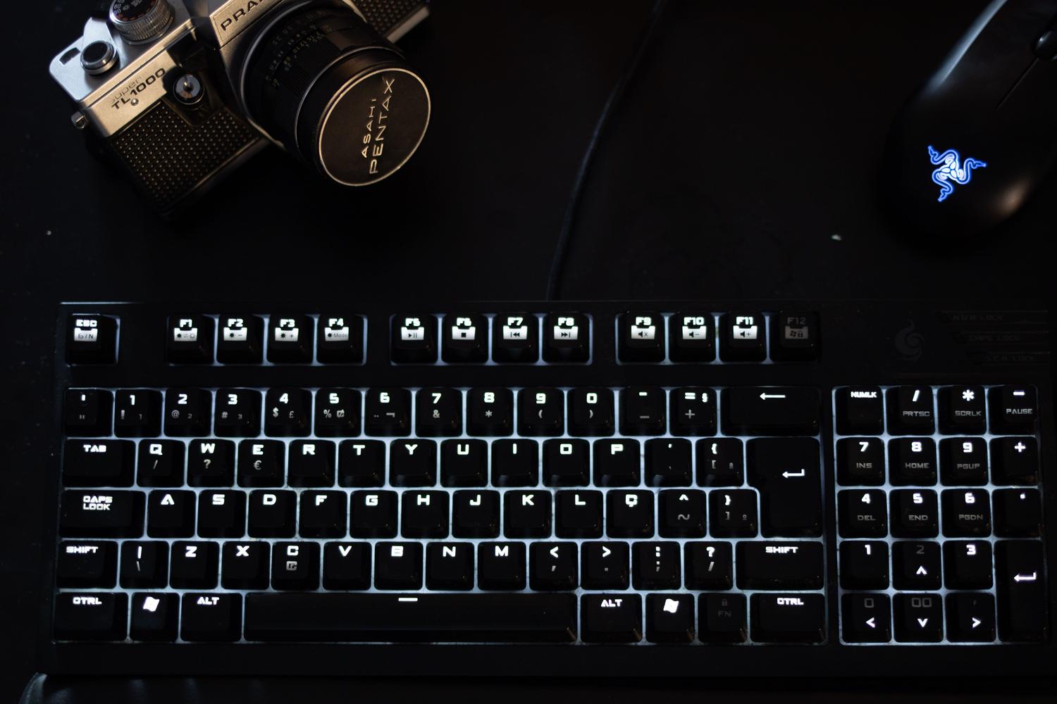 Configuración de escritorio profesional con teclado mecánico iluminado y ratón gaming, representando un entorno de trabajo optimizado.