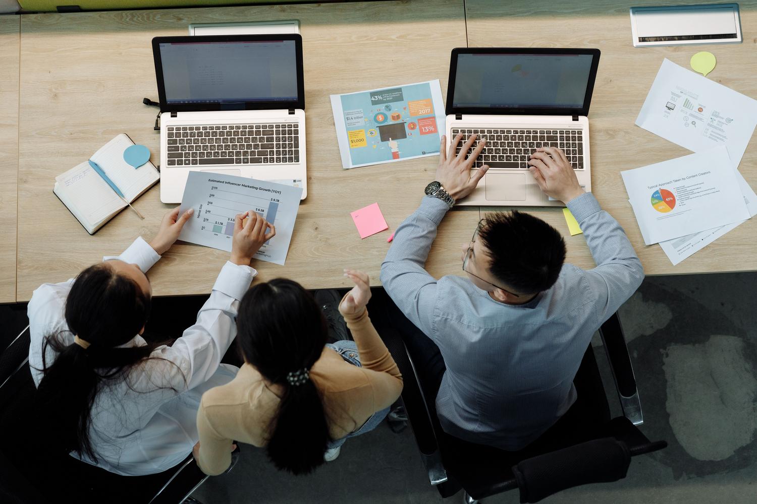 Equipo diverso de profesionales colaborando con ordenadores portátiles en una oficina moderna.