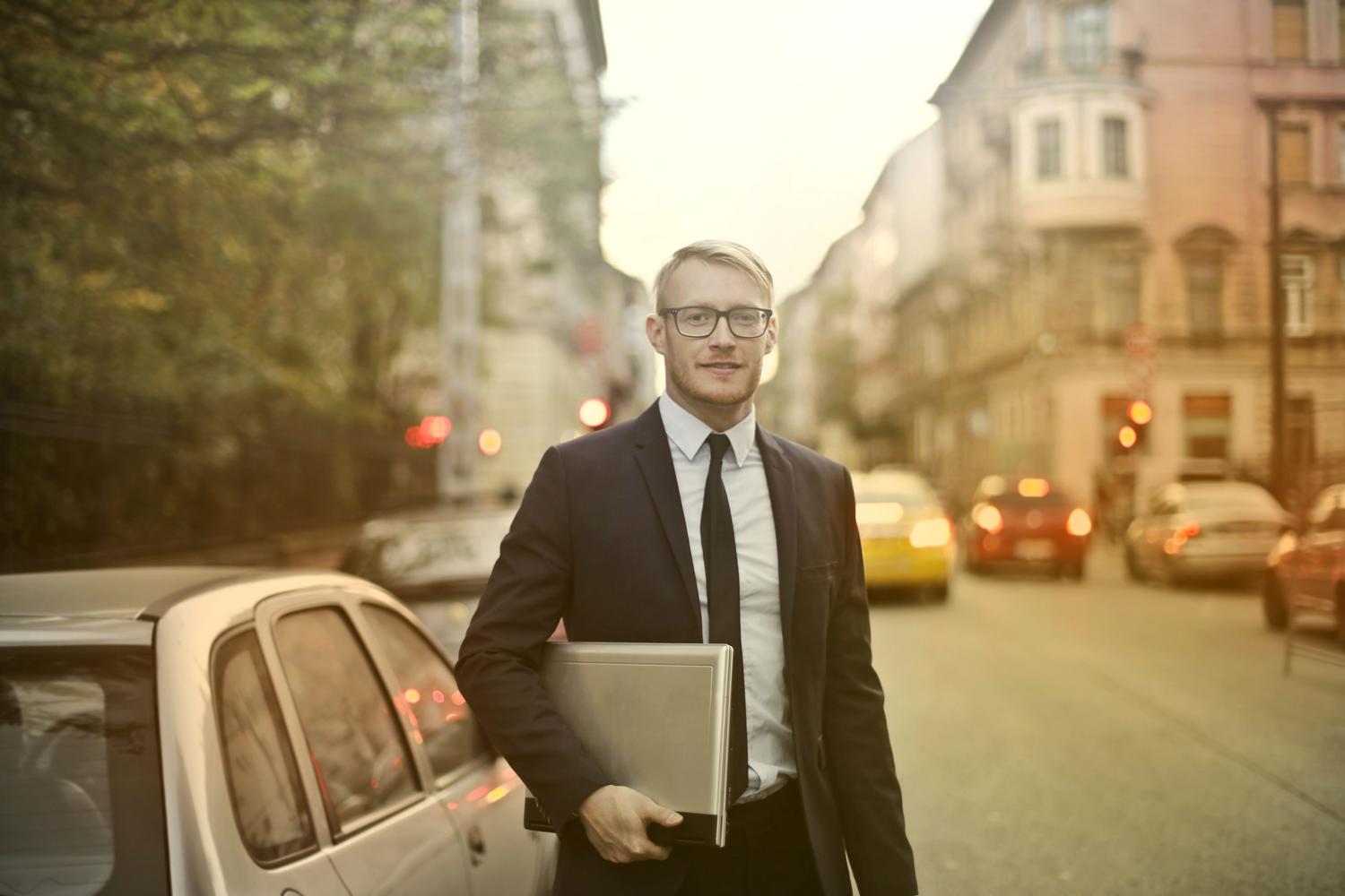 Retrato profesional de un emprendedor seguro de sí mismo con un ordenador portátil, representando la optimización del perfil como página de ventas.