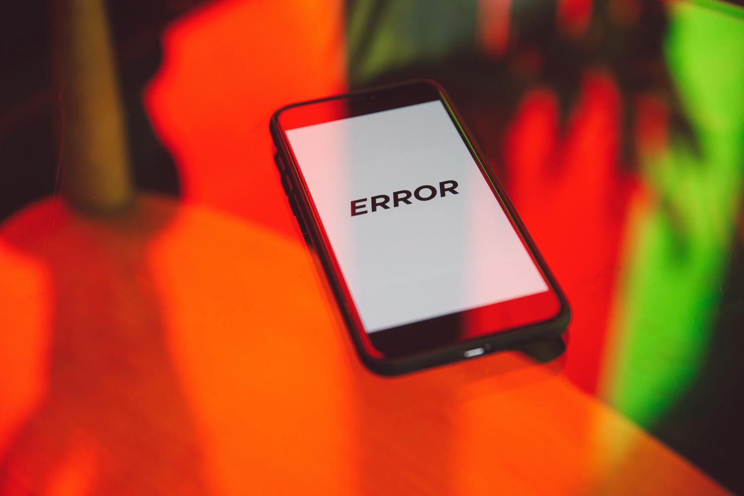 Smartphone mostrando la palabra ERROR sobre un fondo de luces rojas y verdes, ilustrando fallos digitales y alucinaciones de IA