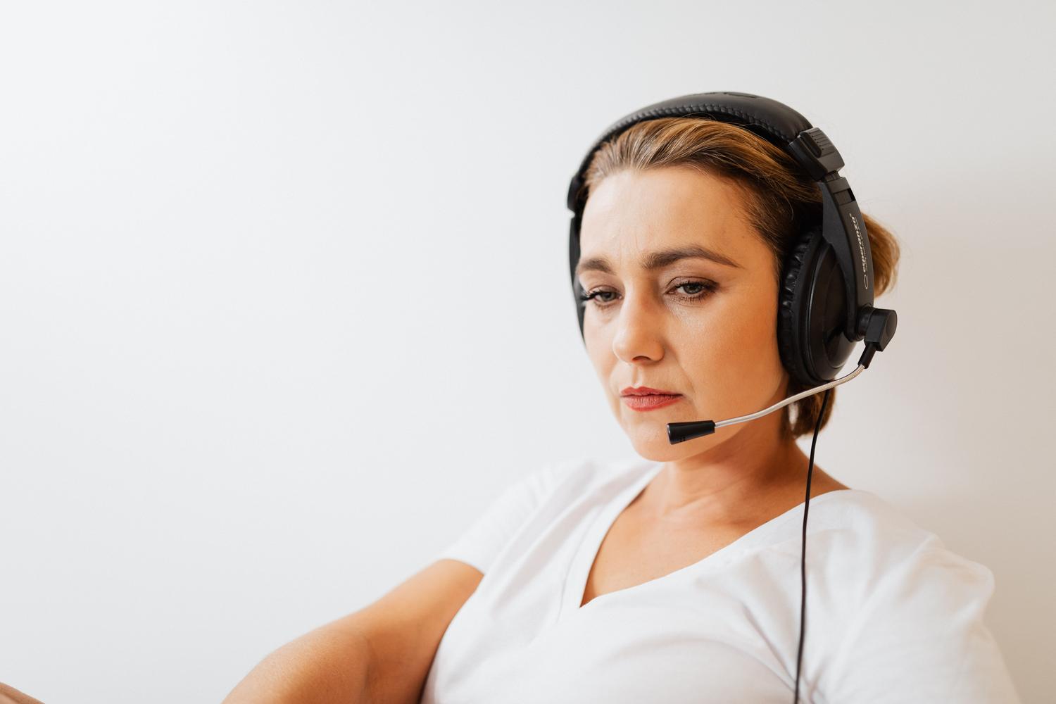 Agente de soporte al cliente enfocada y profesional utilizando auriculares sobre un fondo blanco. Agente de soporte al cliente enfocada y profesional utilizando auriculares sobre un fondo blanco.