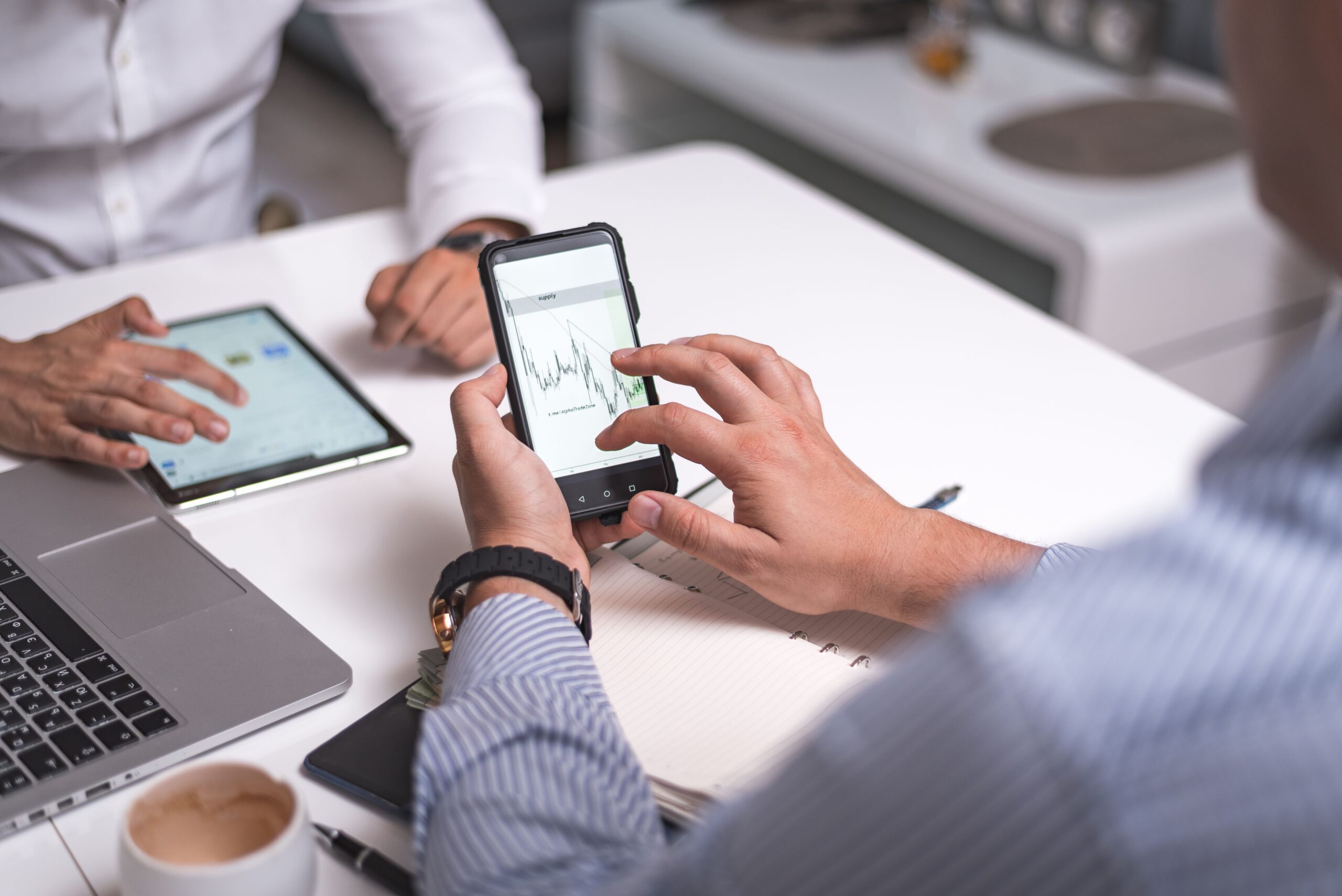 Profesionales colaborando en el análisis estratégico de finanzas utilizando tablets y smartphones.