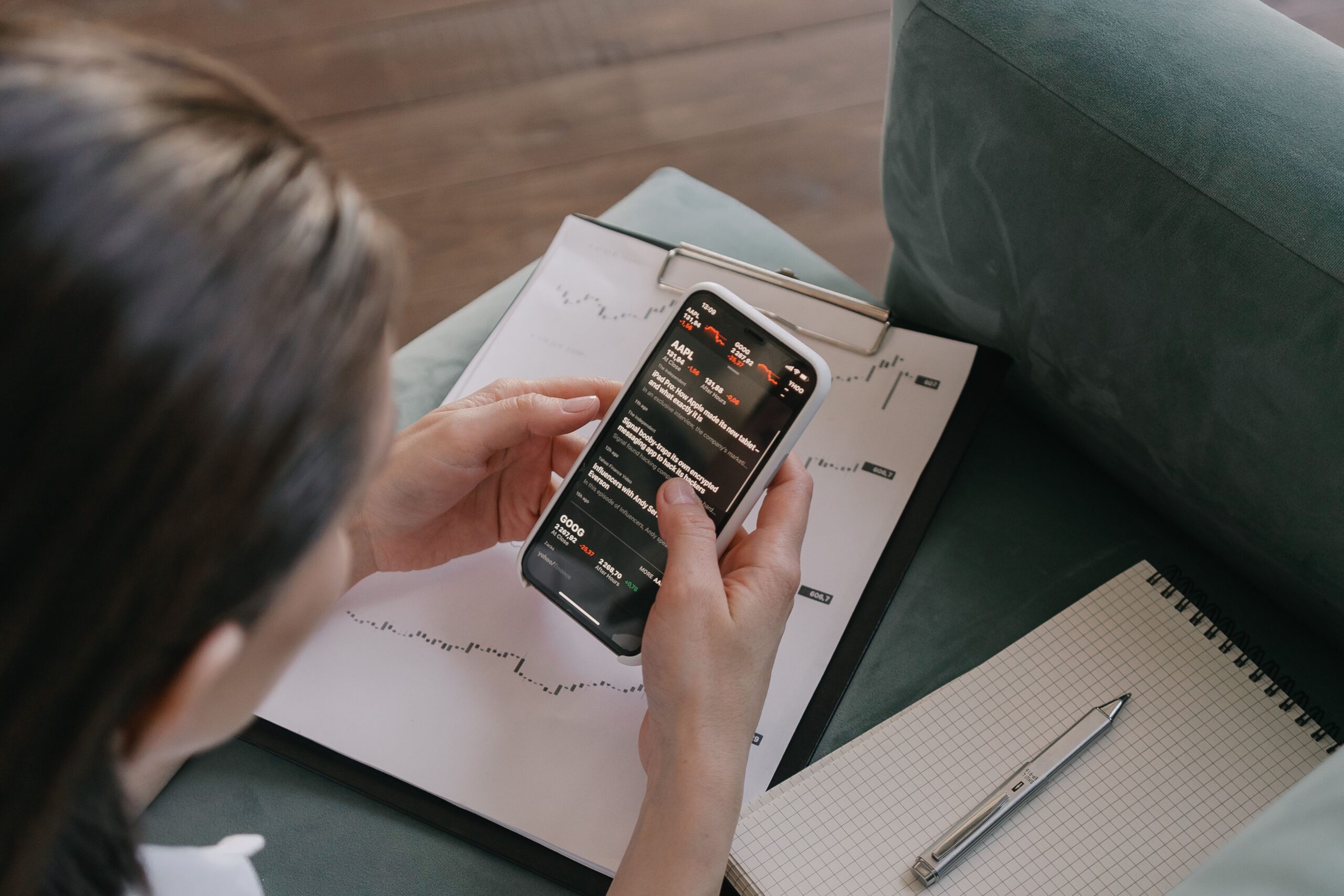 Mujer utilizando un asistente financiero móvil para analizar datos personalizados junto a reportes físicos.