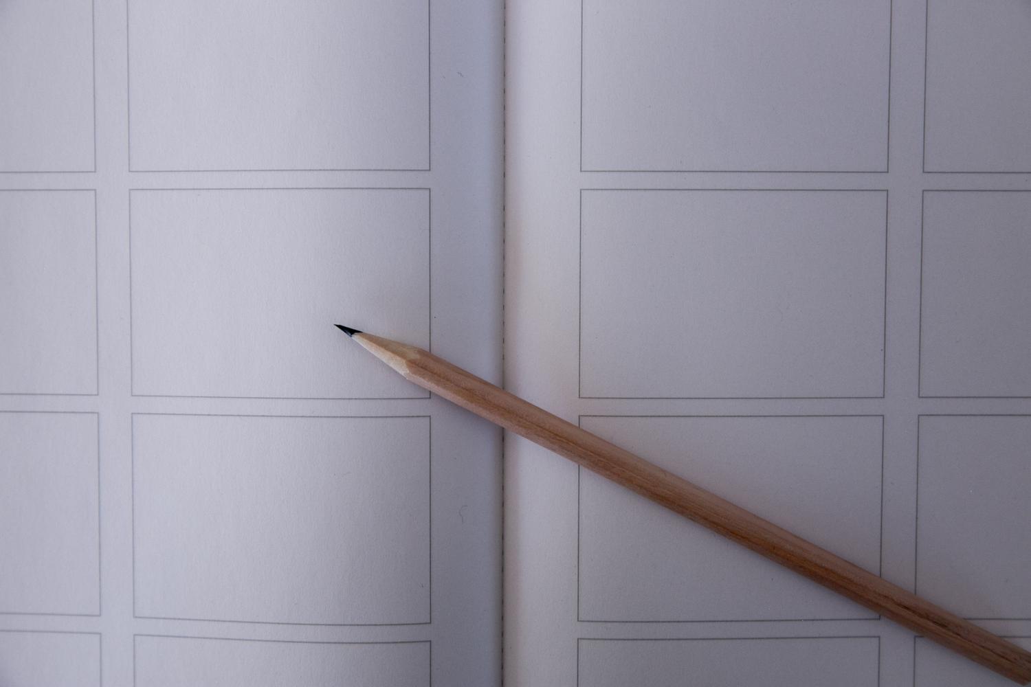 Vista cenital de un cuaderno de storyboard con paneles vacíos y un lápiz, ilustrando la planificación visual inicial.