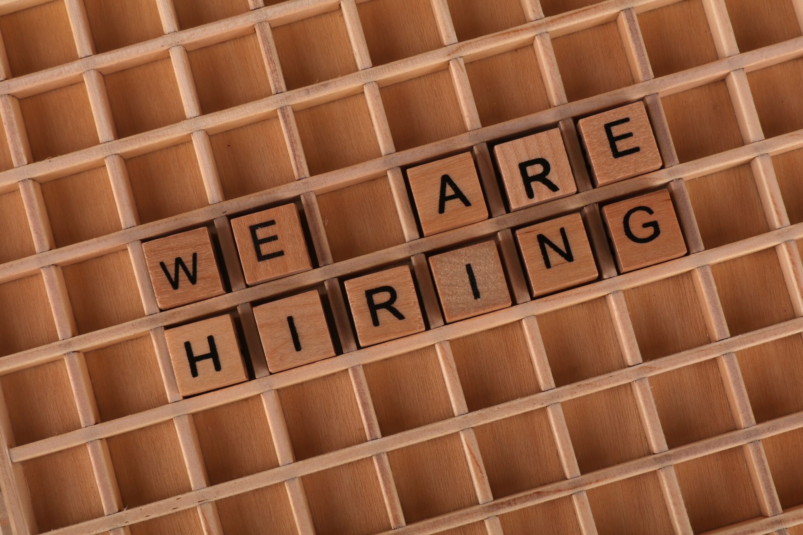 Fichas de madera formando la frase 'We Are Hiring', representando los procesos de reclutamiento y selección automatizados.