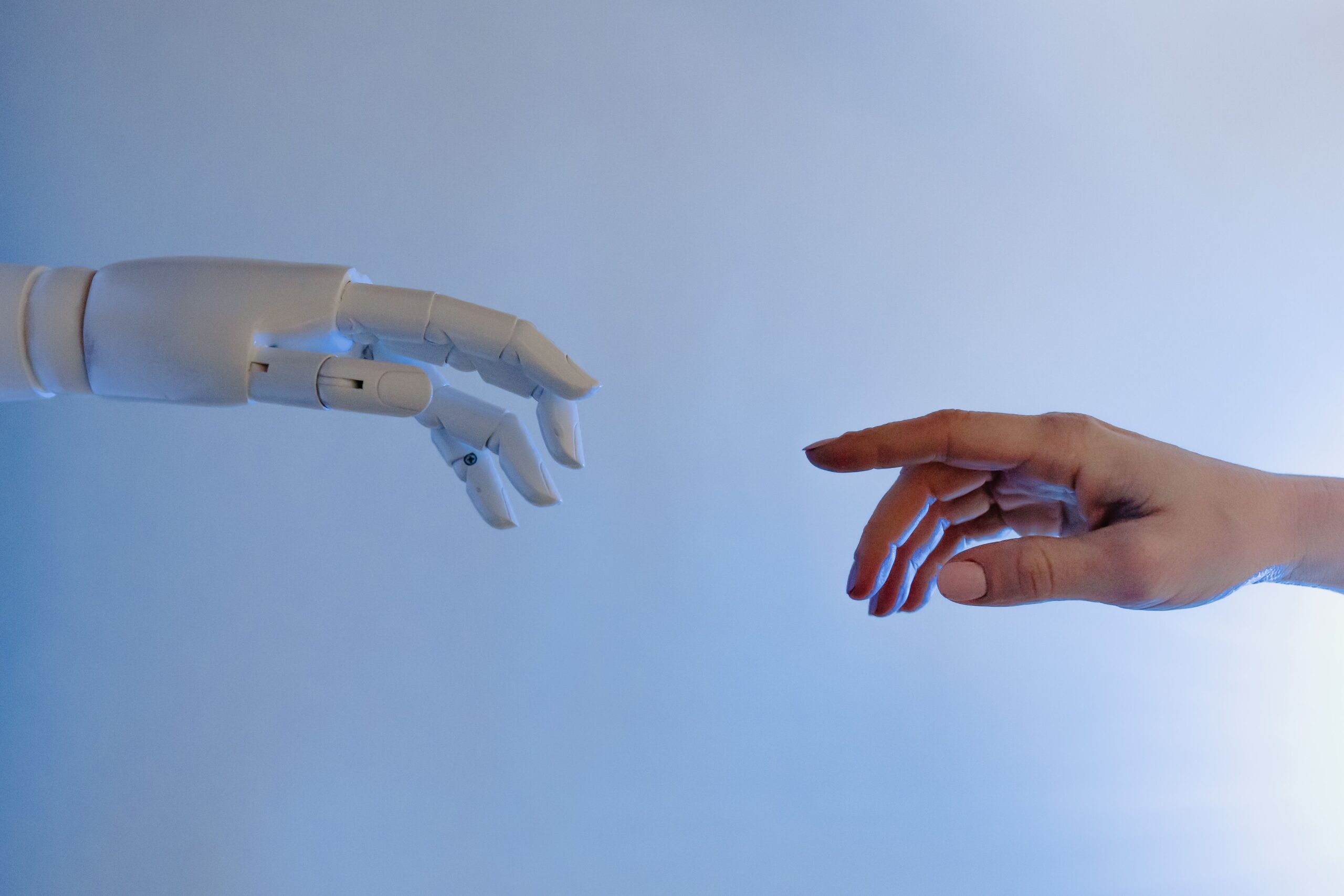 Una mano humana y una mano robótica acercándose para tocarse, simbolizando la colaboración entre la inteligencia artificial y el talento humano en RRHH.