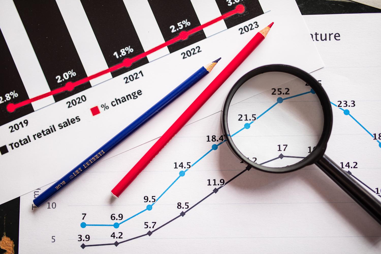 Lupa analizando puntos máximos de un gráfico de ventas, metáfora visual del proceso de lead scoring y priorización de leads.