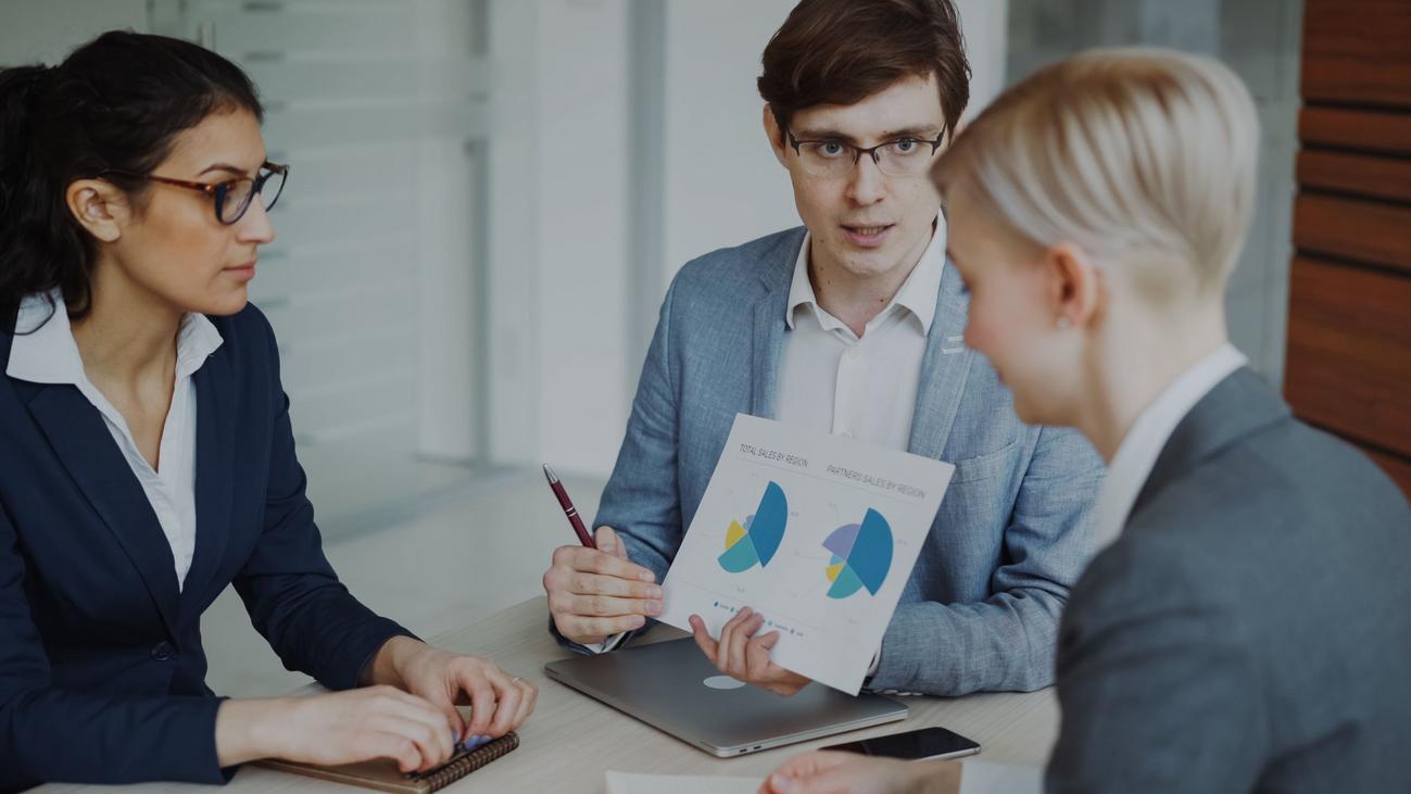 Equipo de ventas profesional analizando estrategias y gráficas de crecimiento en una oficina moderna.