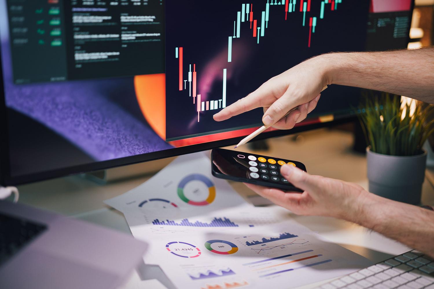 Análisis de datos en tiempo real utilizando un monitor con gráficos de velas japonesas y un smartphone, ilustrando la agilidad digital.