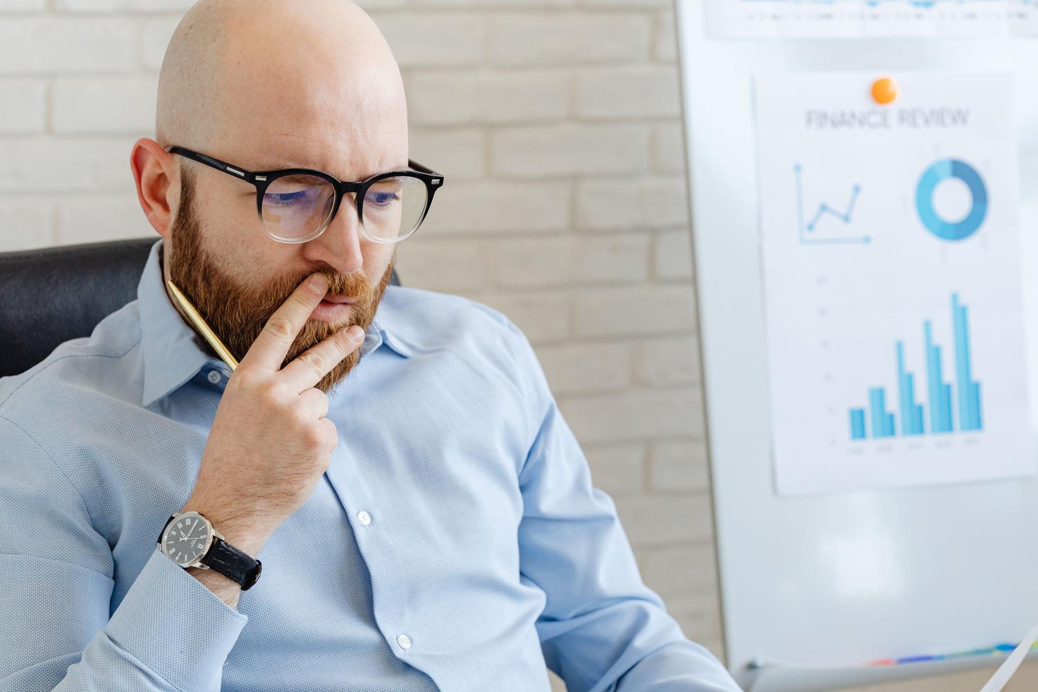 Profesional analizando una revisión financiera en una pizarra con gráficos de tendencias y barras, destacando la supervisión humana en la estrategia.