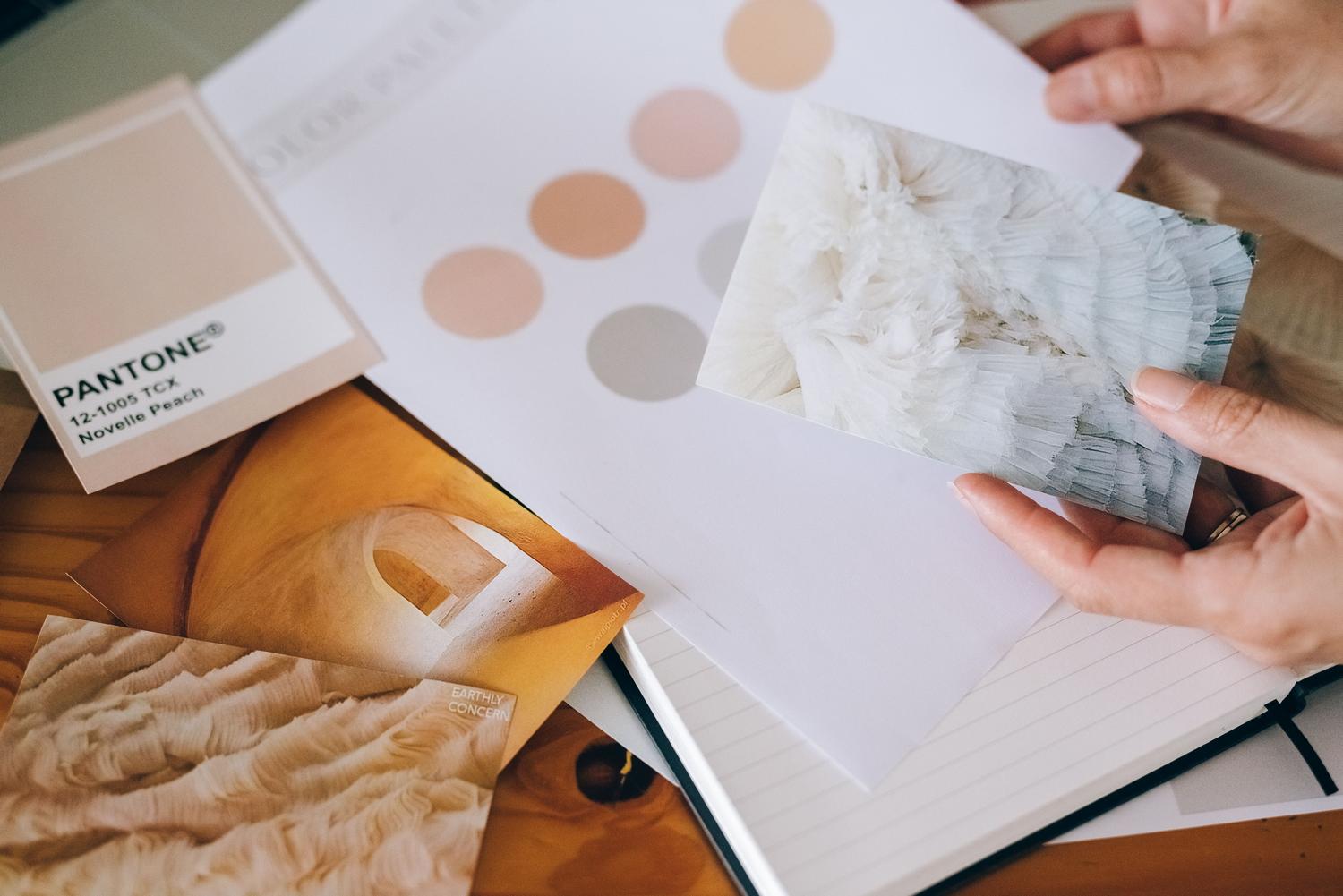 Detalle de un moodboard profesional con paletas de colores Pantone, texturas y referencias visuales sobre un cuaderno de diseño.