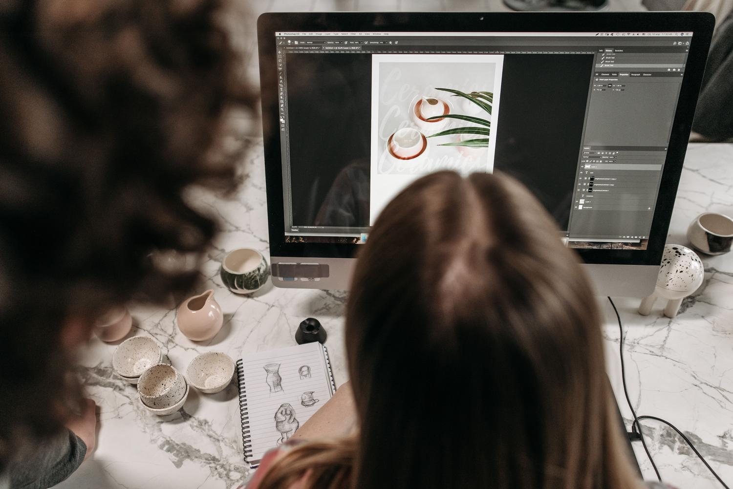 Dos diseñadores colaborando en la edición digital de un proyecto, representando la supervisión humana en el proceso creativo con IA.