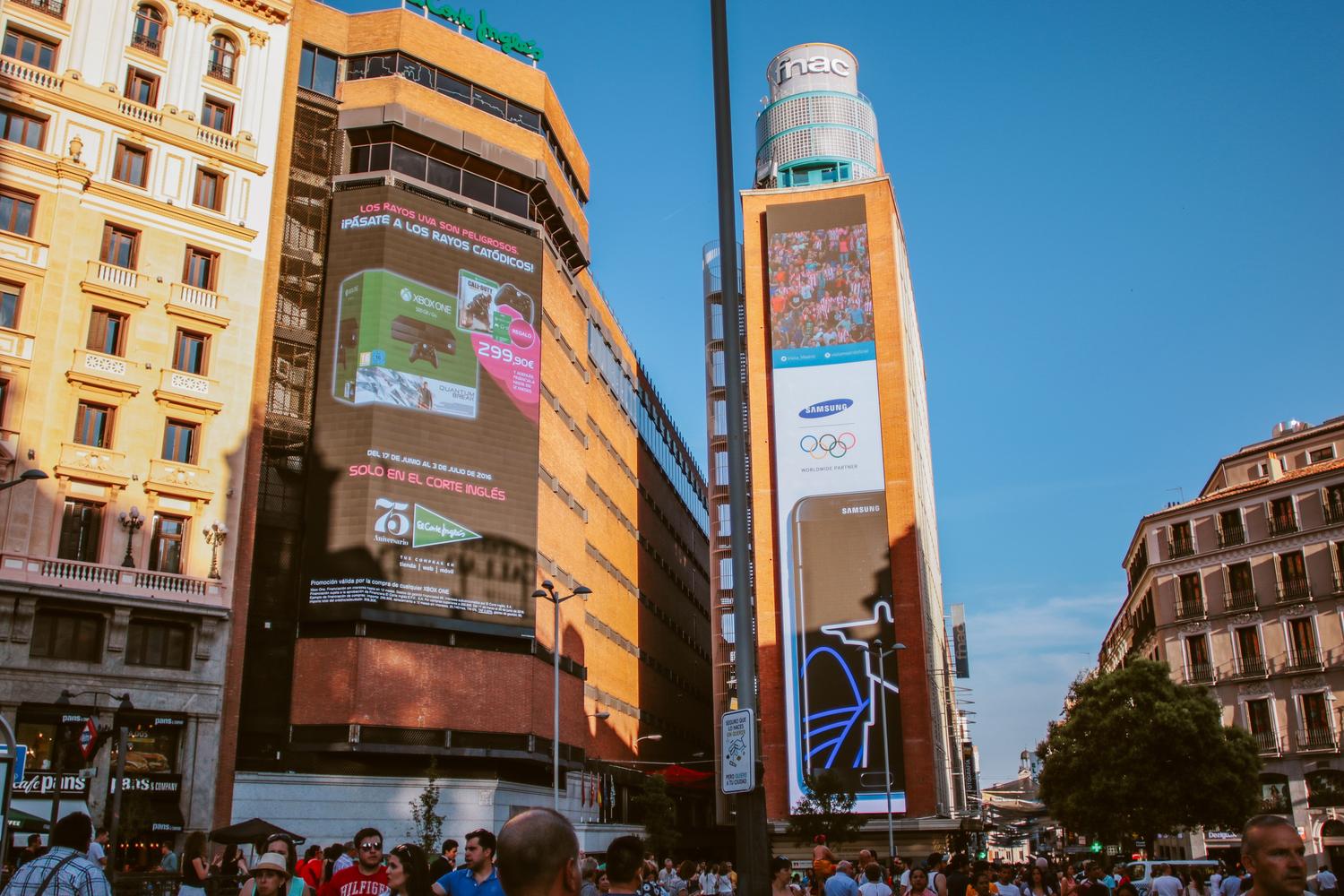 Vista de una plaza urbana saturada de pantallas publicitarias digitales gigantes, representando el desafío de destacar en un entorno digital competitivo.