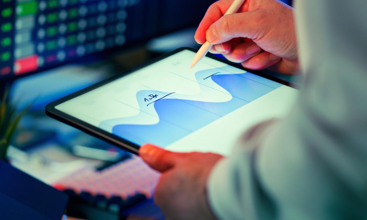 Profesional analizando gráficos de datos en una tablet con lápiz óptico, ideal para ilustrar el análisis de hipótesis y datos en la gestión de producto.