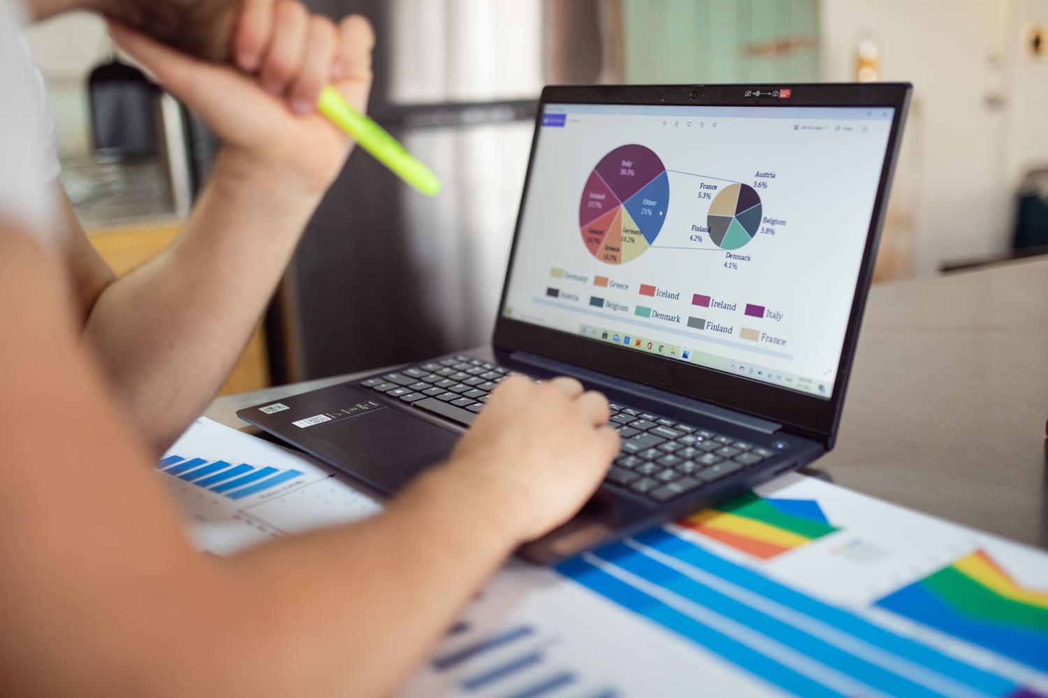 Persona analizando gráficos financieros y datos en un ordenador portátil, representando la productividad y el análisis de datos mediante herramientas de IA.