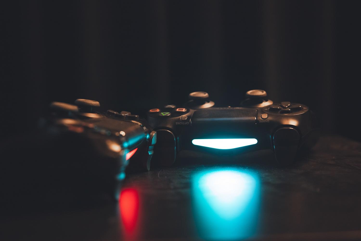 Mandos de juego con luces LED azules y rojas sobre una superficie oscura, simbolizando la conectividad inalámbrica y el entorno gaming.