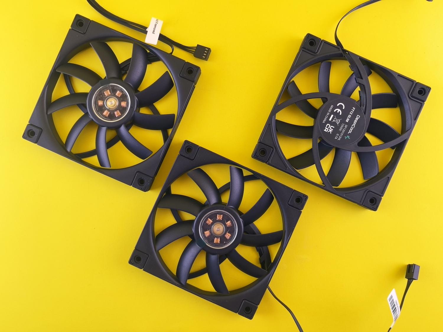 Tres ventiladores de refrigeración para ordenador sobre un fondo amarillo vibrante.