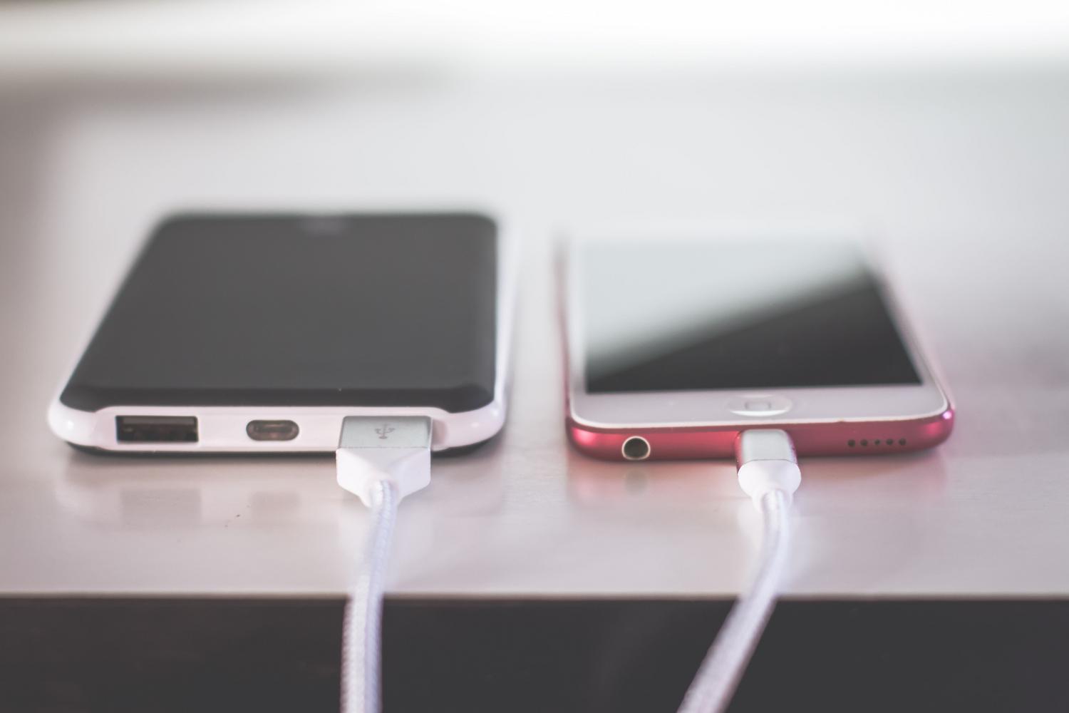 Dos iPhones cargando simultáneamente sobre un escritorio, representando la solución básica de recarga de energía.