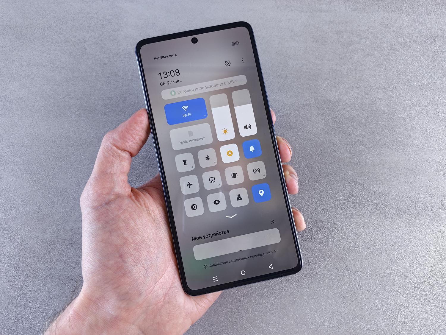 Primer plano de una mano sosteniendo un smartphone con el panel de ajustes abierto, representando la optimización del sistema y el consumo de batería.