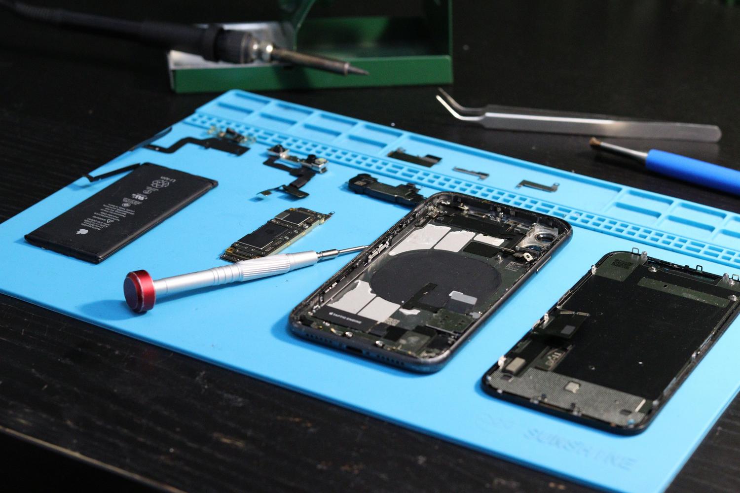 Componentes de un smartphone desmontado sobre una manta de reparación técnica, ilustrando la necesidad de sustituir la batería o acudir al servicio técnico.