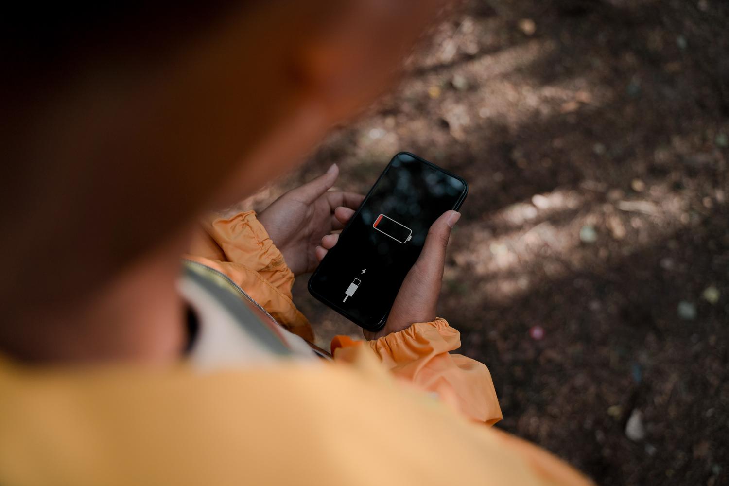 Persona sosteniendo un smartphone que muestra un aviso de batería baja