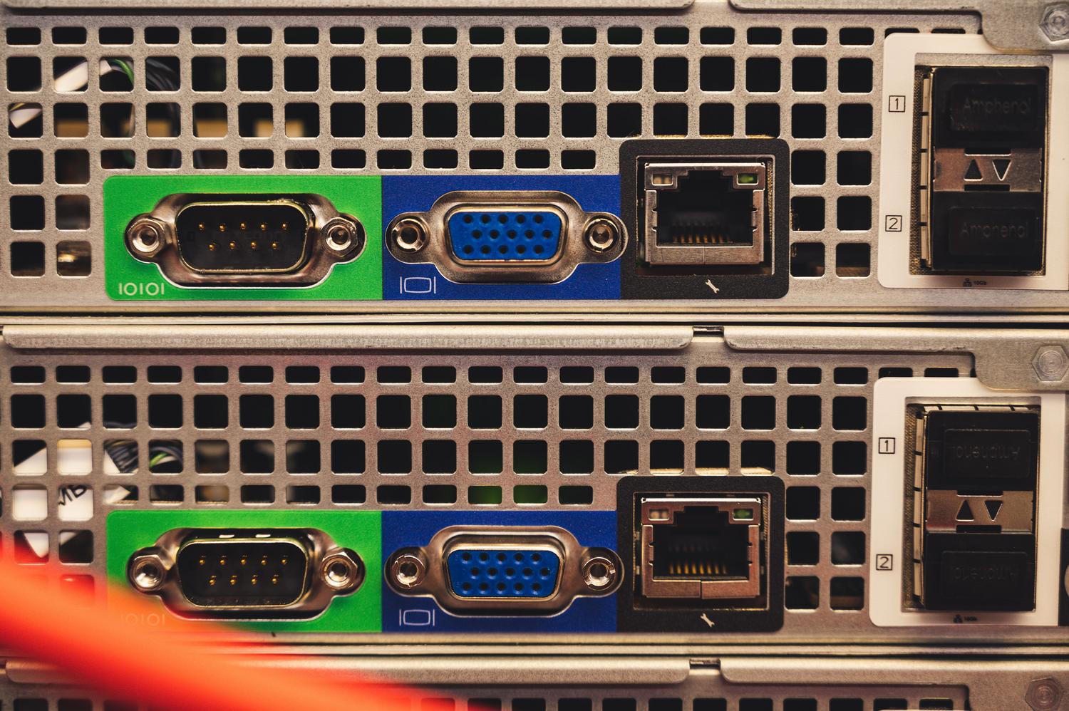 Detalle de puertos de servidor con conexiones seriales, VGA y Ethernet, ejemplificando la coexistencia de estándares antiguos y modernos.