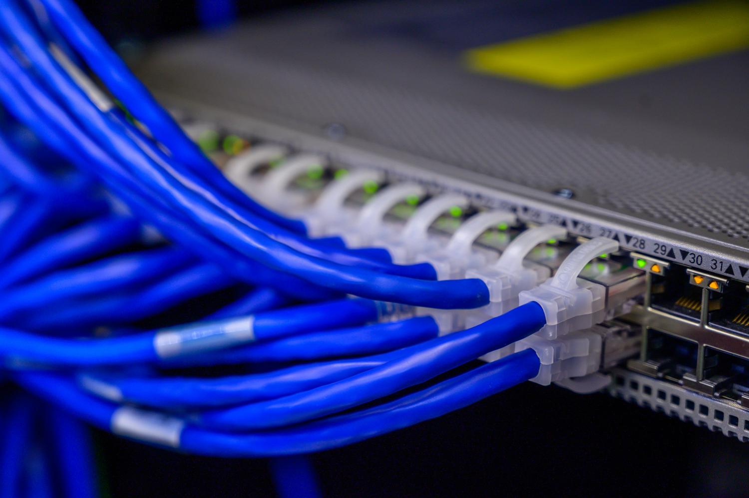 Switch de red con múltiples cables Ethernet azules conectados, representando la interconectividad y las capas del modelo TCP/IP.
