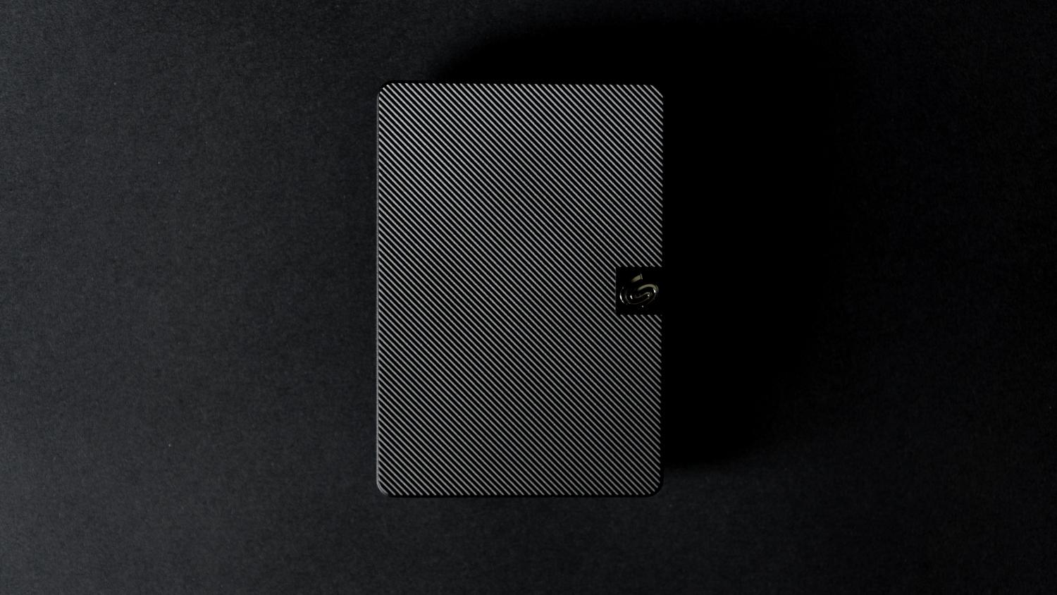 Imagen detallada de un disco duro externo moderno sobre fondo negro.