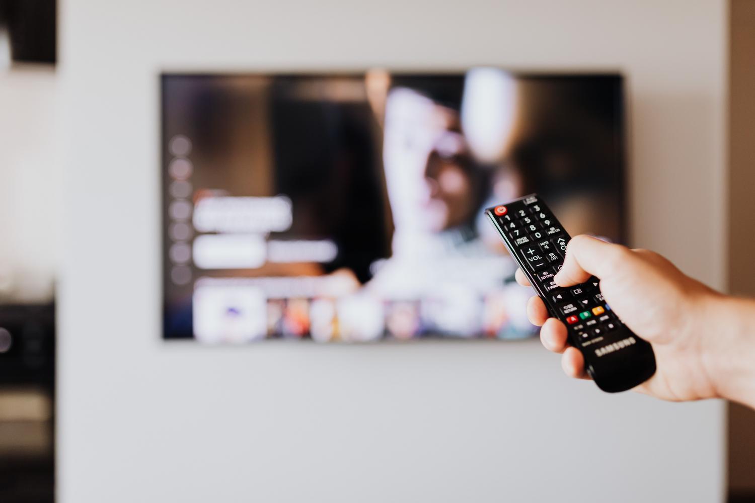 Persona utilizando el mando a distancia para navegar por los ajustes de sonido de un televisor