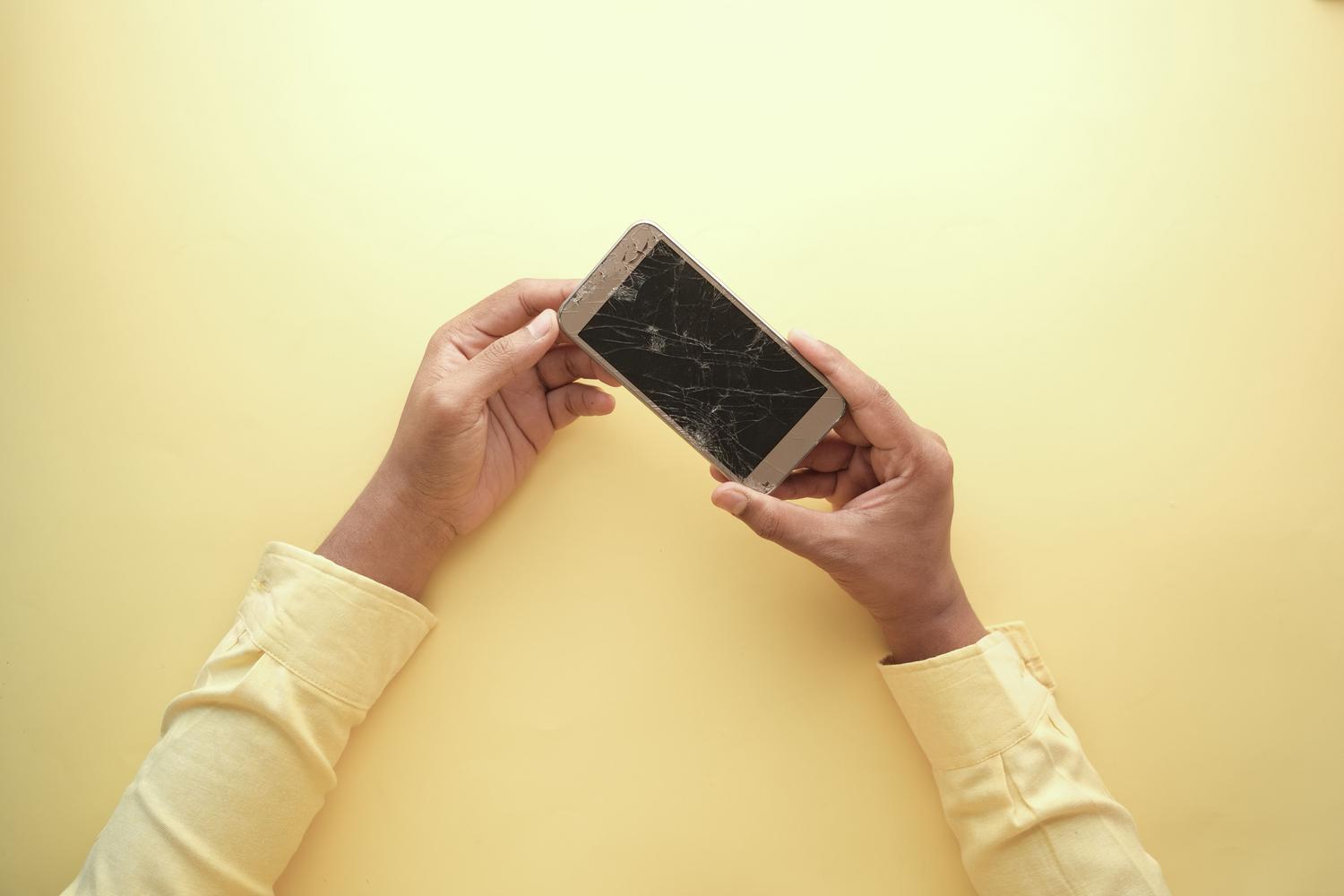 Primer plano de una pantalla de móvil rota y agrietada que afecta al táctil