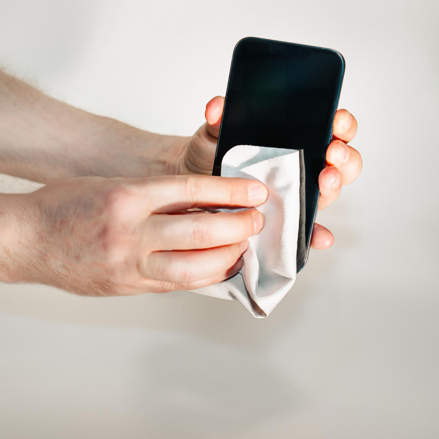 Limpieza de la pantalla de un smartphone con un paño de microfibra para eliminar suciedad