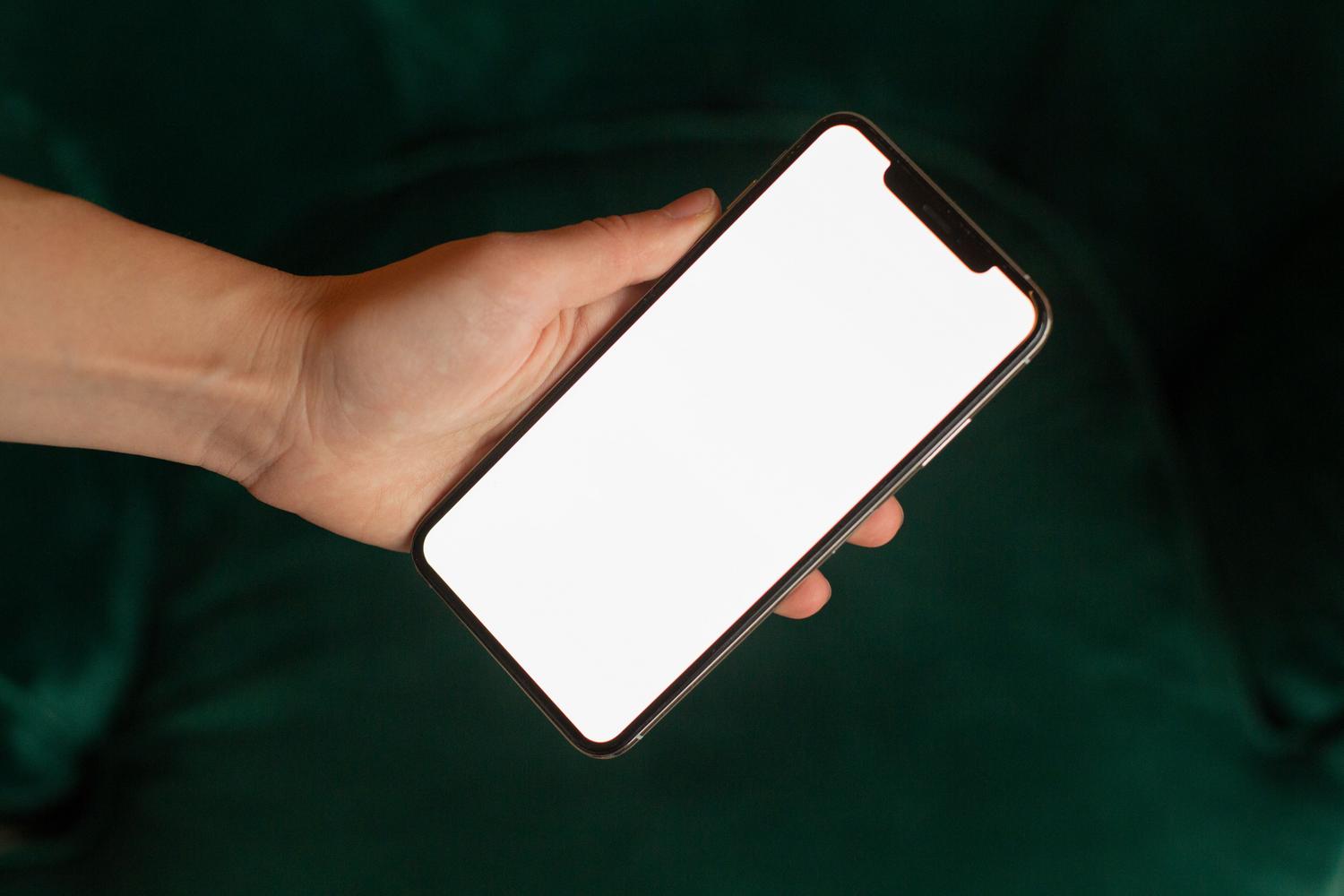 Mano sosteniendo un dispositivo móvil con pantalla en blanco, ideal para representar diagnósticos de software