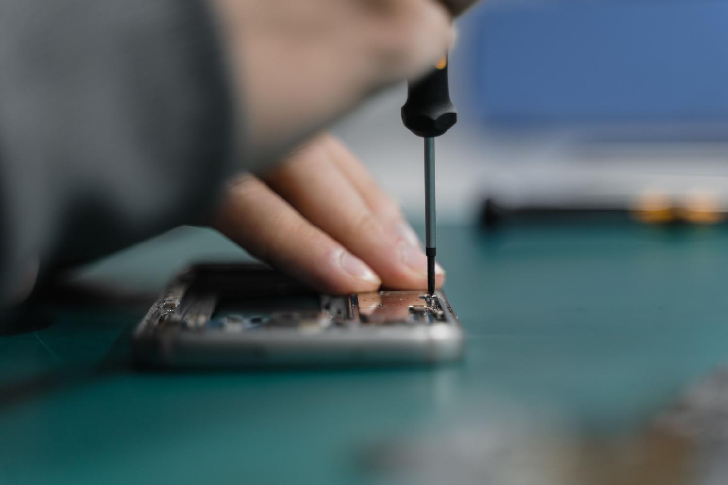 Técnico especializado reparando la pantalla de un teléfono móvil con herramientas de precisión