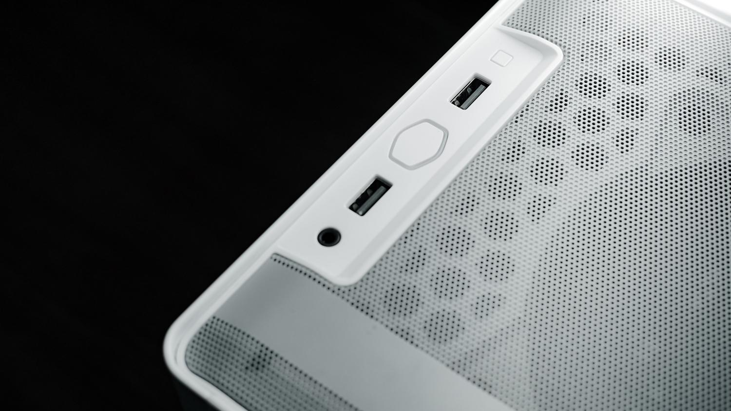 Primer plano detallado de los puertos USB y conectores de audio en el panel frontal de una caja de PC blanca.