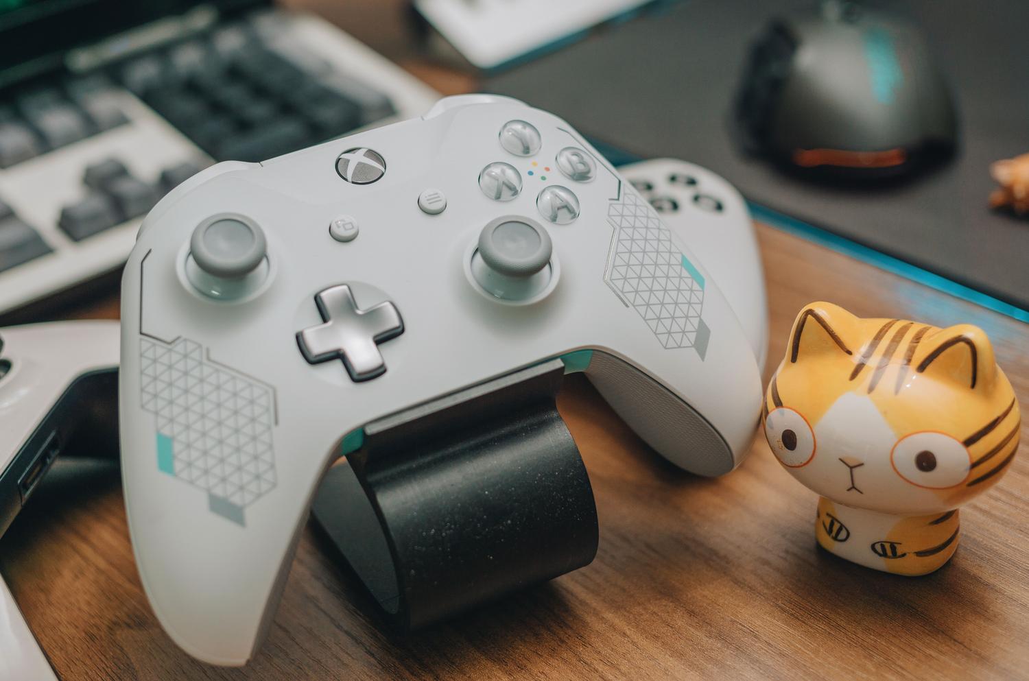 Primer plano de un mando de Xbox blanco sobre un escritorio de madera en un entorno de gaming