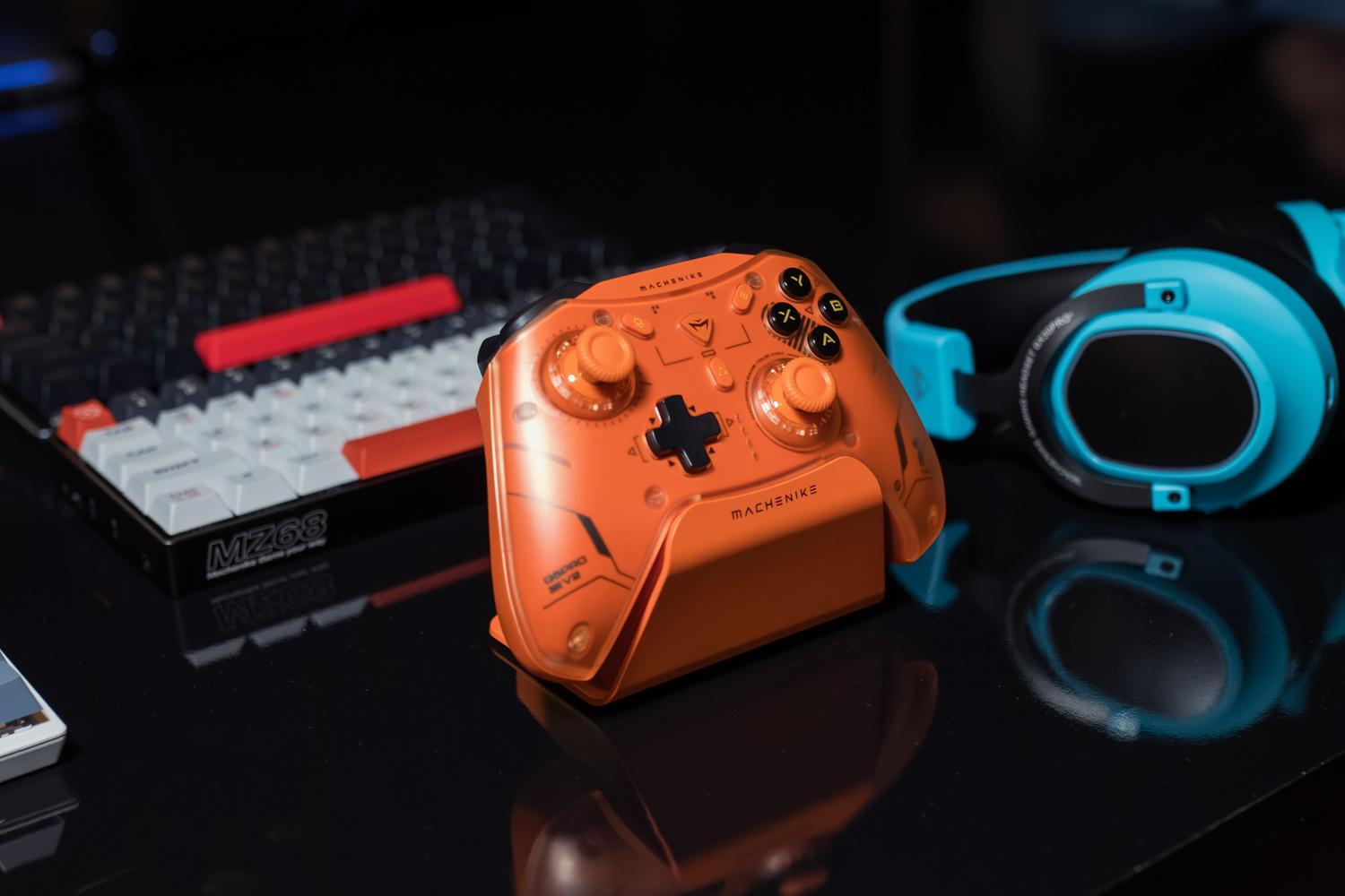 Set de gaming completo con mando naranja, teclado mecánico y auriculares azules sobre una superficie negra