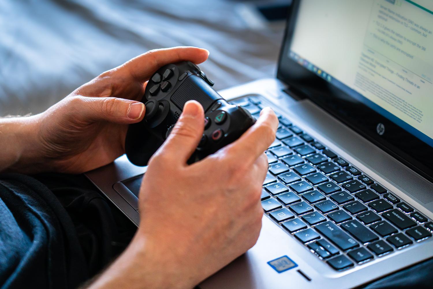 Persona utilizando un mando de gaming sobre el teclado de un portátil mientras consulta una guía de solución de problemas