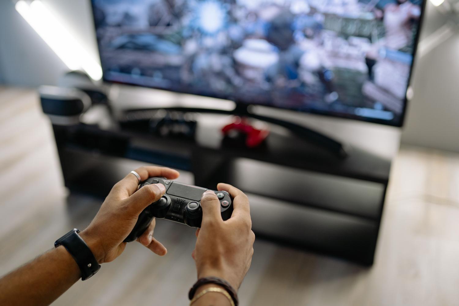 Vista en primera persona de un jugador sosteniendo un mando de PlayStation, ilustrando la experiencia de uso
