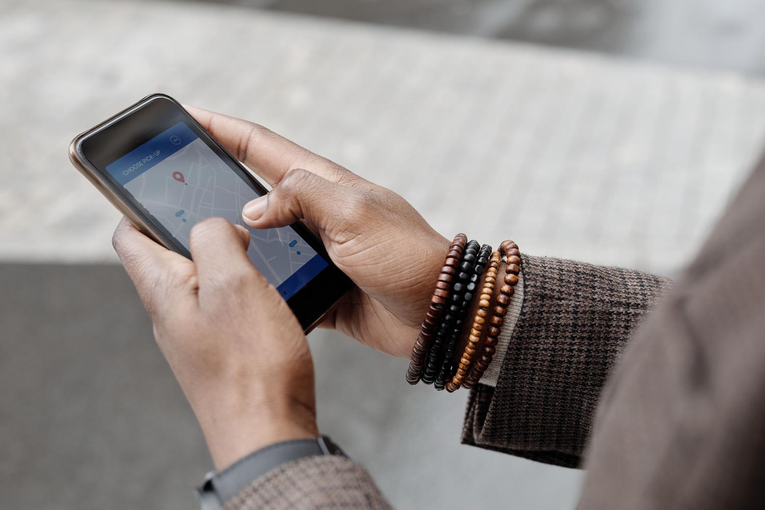 Detalle de manos utilizando el GPS de un teléfono móvil para buscar una ubicación en el exterior, ideal para representar el concepto de SEO Local.