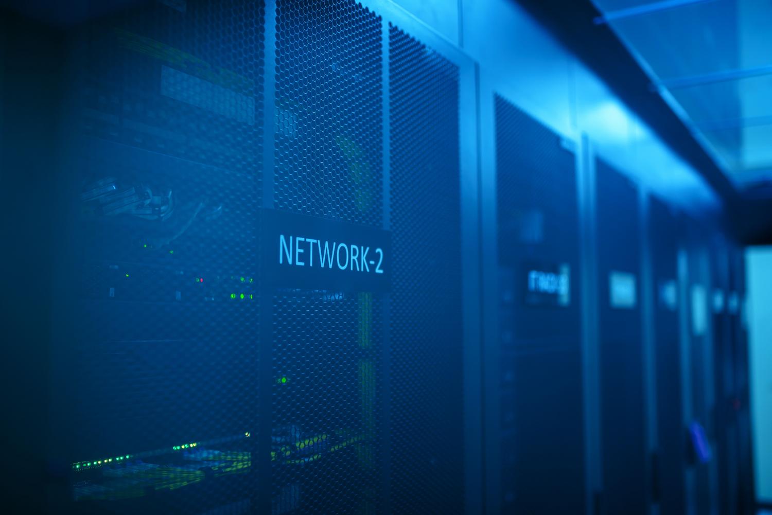 Corridor of a modern data center with server racks illuminated in blue, representing the infrastructure where Linux firewalls are deployed.
