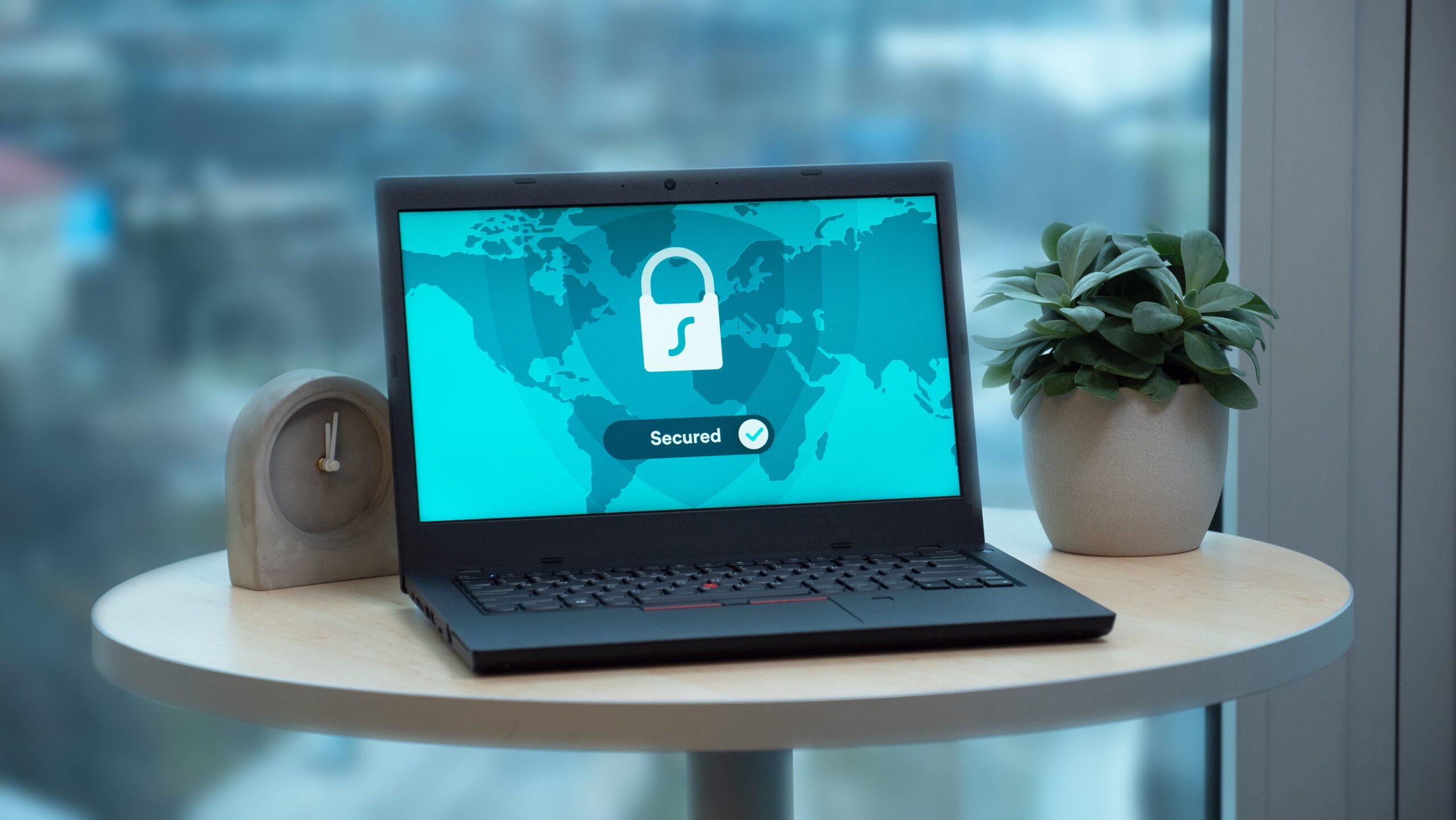 Pantalla de laptop con un icono de candado y el estado 'Secured', simbolizando la protección del sistema y el blindaje de datos.